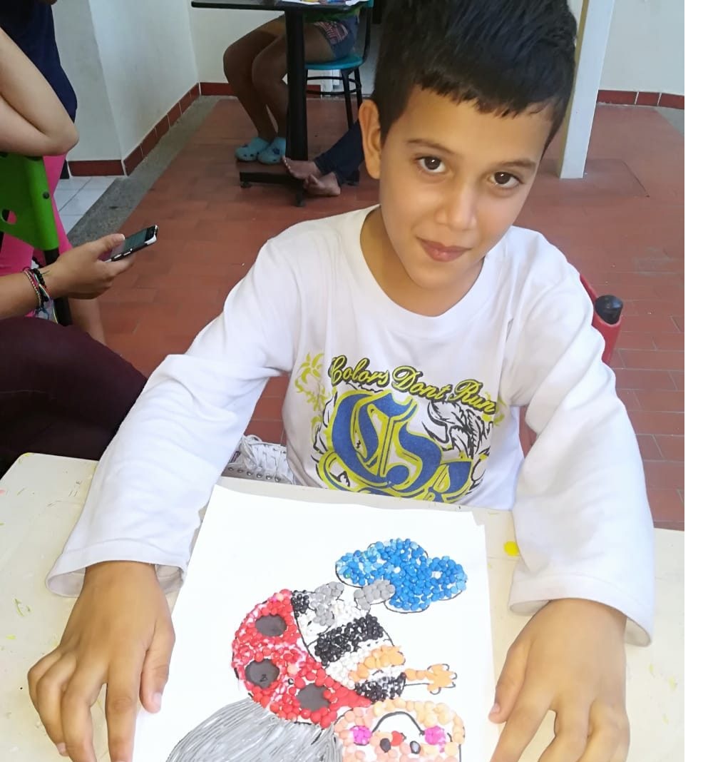 Niño mostrando su trabajo artístico en el hogar de paso